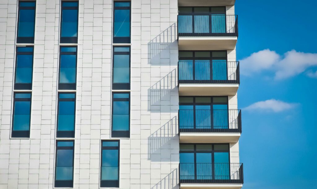 Contemporary urban apartment building with framed glass windows against clear blue sky.